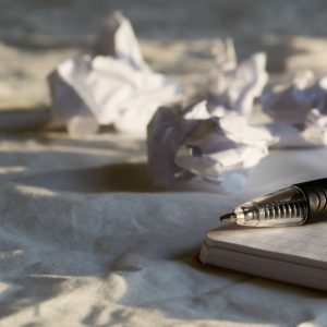 Picture of pen and notepad with wadded up papers