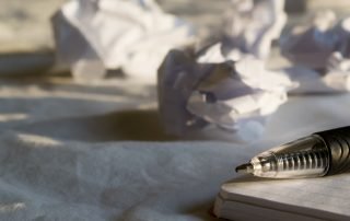 Picture of pen and notepad with wadded up papers
